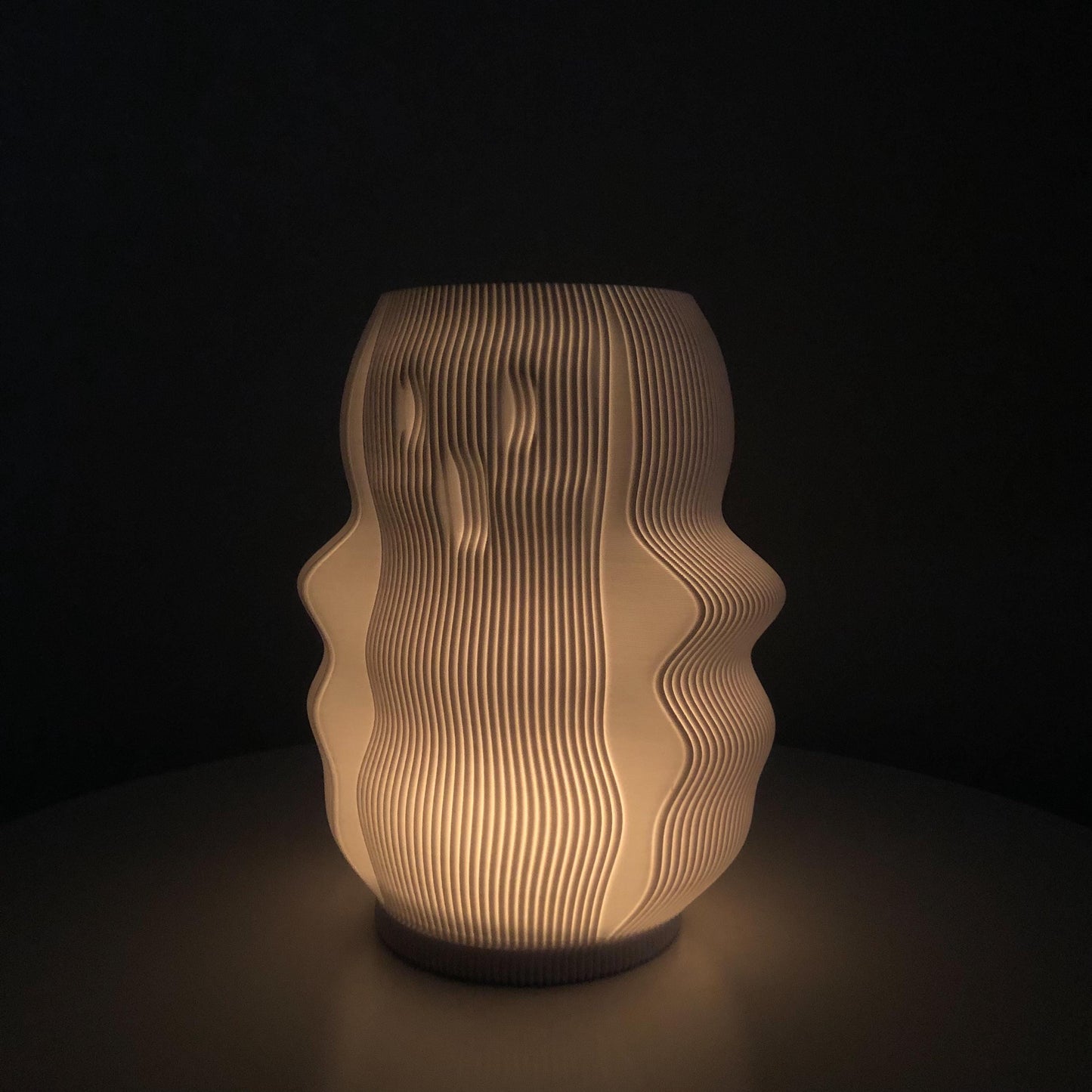 A 3D-printed Boo Lamp in the shape of a ghost, glowing softly with an LED light inside, creating a spooky Halloween ambiance. The ghost has simple, rounded features with hollow eyes and mouth, casting a warm, eerie light.