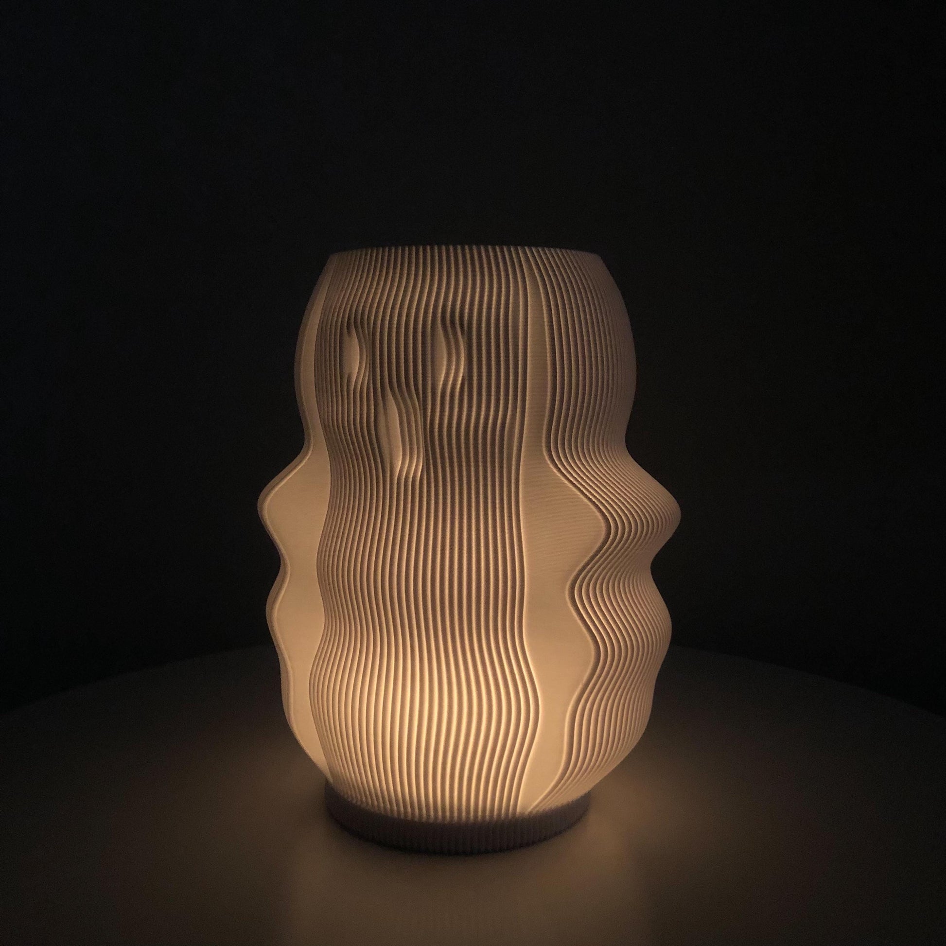 A 3D-printed Boo Lamp in the shape of a ghost, glowing softly with an LED light inside, creating a spooky Halloween ambiance. The ghost has simple, rounded features with hollow eyes and mouth, casting a warm, eerie light.